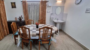 A dining area with a checkered tablecloth, wooden chairs, and a vase of flowers. - 2BR Apartment in the heart of Guwahati (Guwahati)