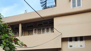 A two-story building with a checkered tile entrance, a parked car, and a tree in the foreground. - 2BR Apartment in the heart of Guwahati (Guwahati)