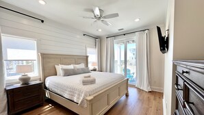 Une chambre à coucher comprenant un lit, une table de chevet, une commode et un ventilateur de plafond.