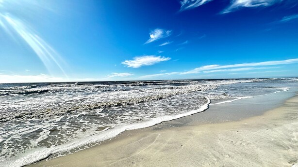 Une plage avec des vagues et un ciel dégagé.