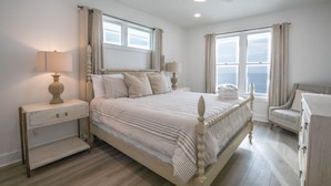 Une chambre à coucher avec un grand lit, deux tables de chevet, une chaise et un ventilateur de plafond.