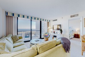 Relax in a stylish room with a comfortable seating area, large window, and beautiful beach view.
