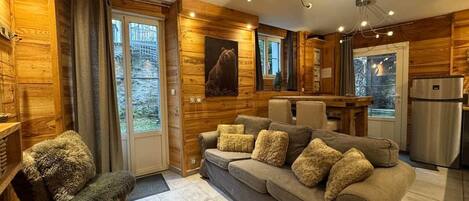 Un salon chaleureux avec un canapé, un fauteuil moelleux et une décoration murale représentant un ours.