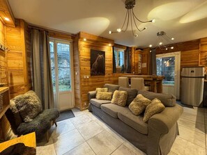 A cozy living room with a sofa, a furry chair, and a bear wall art piece.