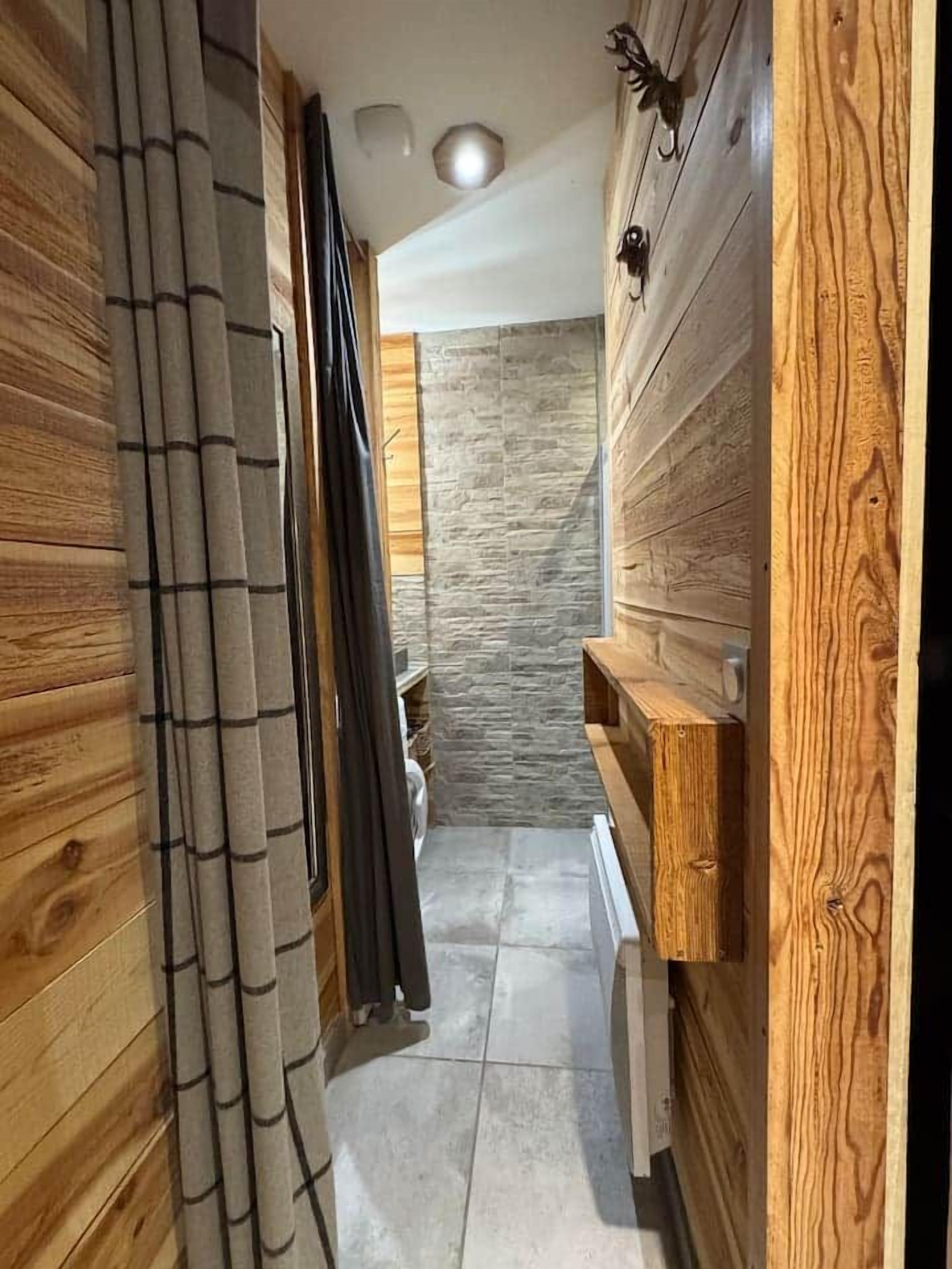 A narrow hallway with wooden paneling and a stone wall.