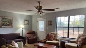 A living room with a brown sofa, two armchairs, a wooden coffee table, and a ceiling fan. - Secluded cabin - 10 miles from Fredericksburg! (Fredericksburg)