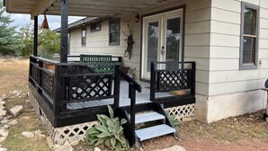 A house with a covered porch, a green bench, and a small staircase leading to the front door. - Secluded cabin - 10 miles from Fredericksburg! (Fredericksburg)