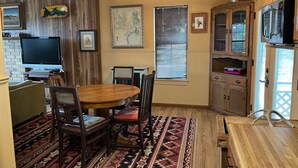 A dining area with a wooden table and chairs, a ceiling fan, and a television on a stand. - Secluded cabin - 10 miles from Fredericksburg! (Fredericksburg)