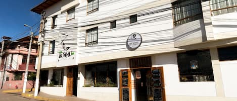 Un edificio de dos pisos con un cartel que dice 'BUNNU CAFE' en la planta baja.