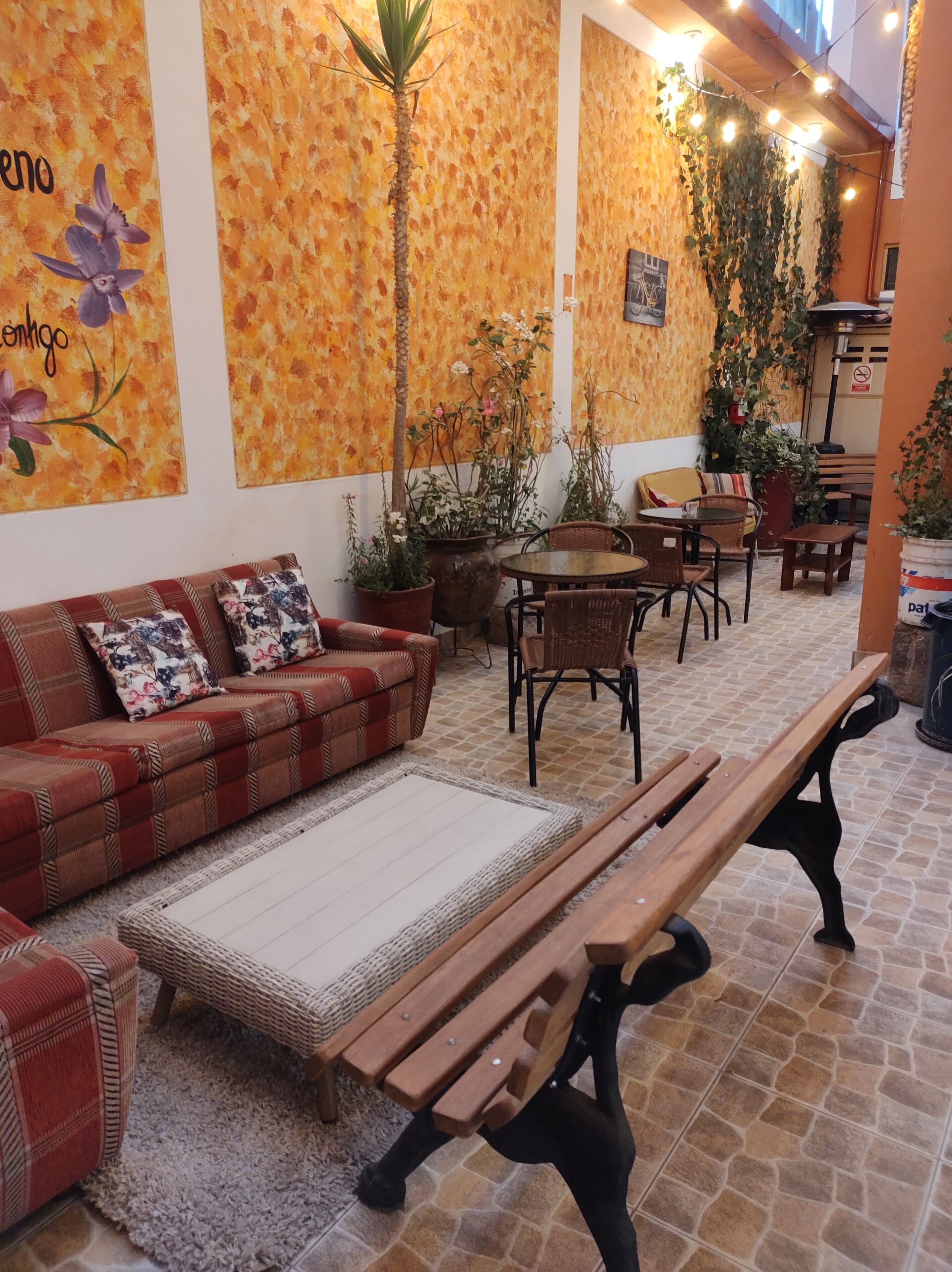 Un área de estar al aire libre acogedora, con un sofá, sillas y una mesa de madera.