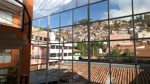 A view through a window of a building with a tiled roof and a cityscape in the background. - Eco Bunnu Inn (Cusco)
