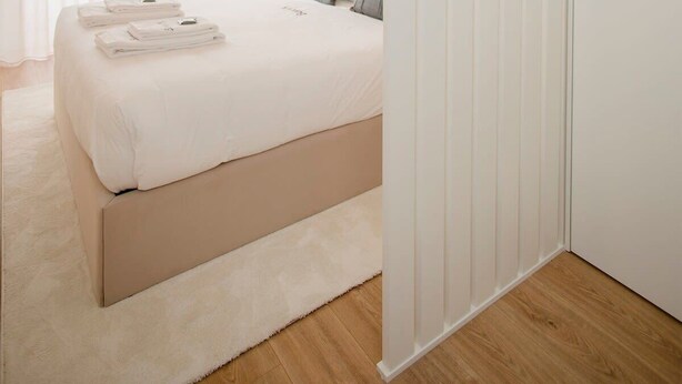 A modern bedroom with a large bed, a fluffy rug, and a white wardrobe.
