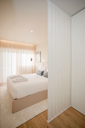 Un dormitorio moderno con una cama grande, una alfombra mullida y un armario blanco.