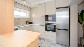 A modern kitchen with stainless steel appliances, a wooden countertop, and a window providing natural light.