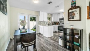 A modern kitchen with white cabinets, a central island, and a built-in microwave.