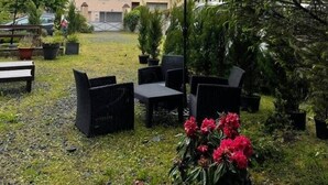 Eine Terrasse mit Gartenmöbeln, ein Gebäude mit geneigtem Dach und eine gebirgige Kulisse.