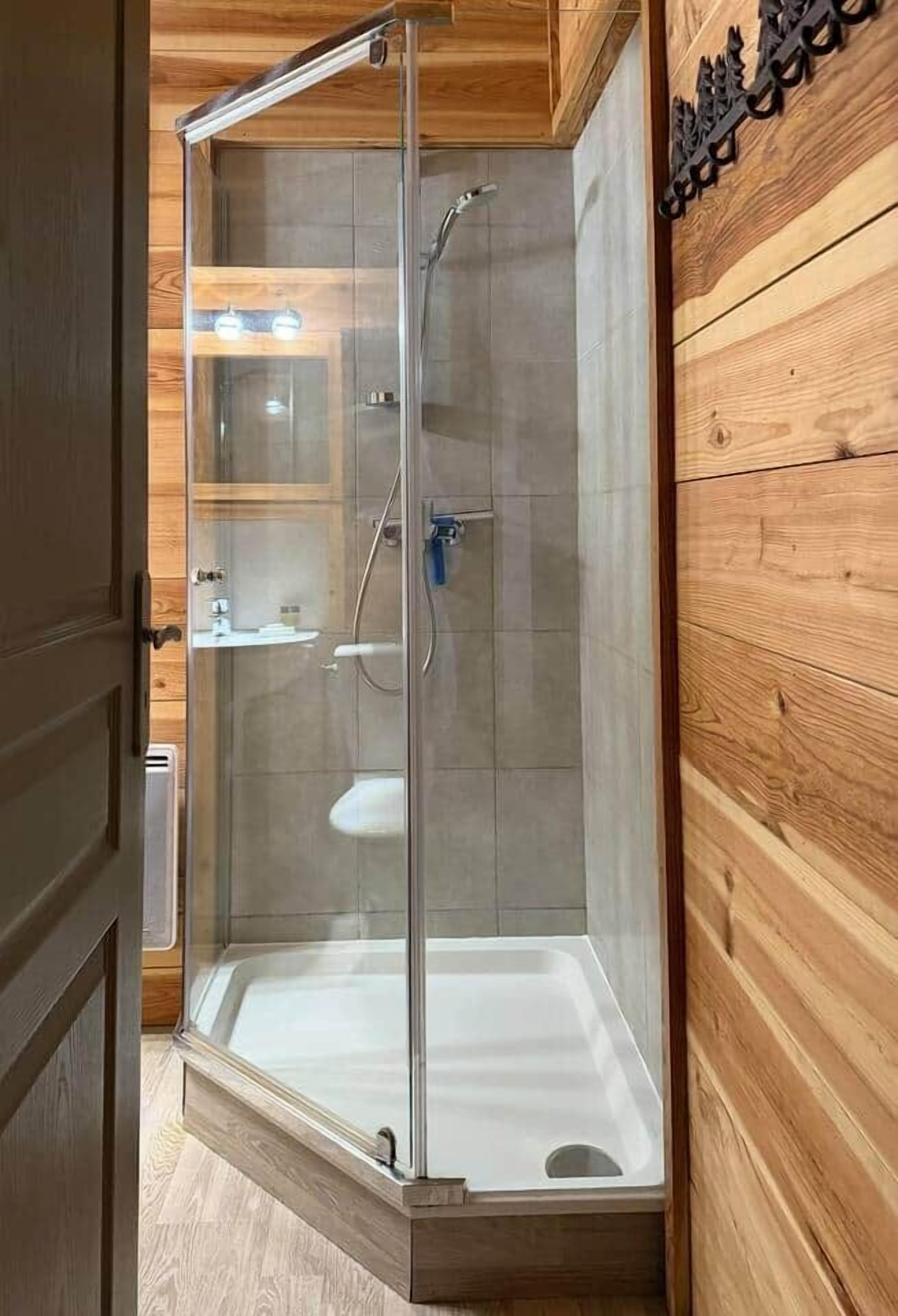 Une cabine de douche moderne dotée d’une porte en verre, d’un banc intégré et d’une étagère fixée au mur.