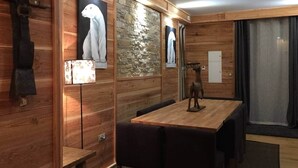 Ein Holzinnenraum mit einem Esstisch, Stühlen, einem Garderobenhaken und gerahmten Kunstwerken an den Wänden.
