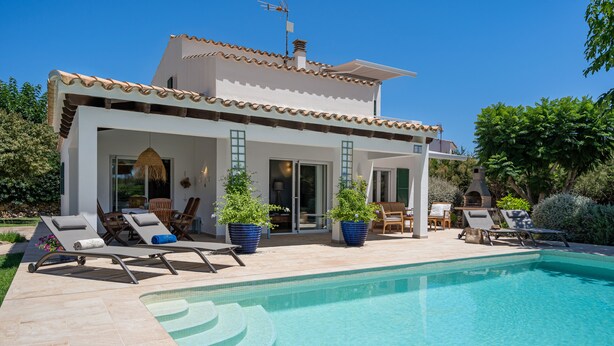 Una casa moderna con piscina, mobiliario exterior y plantas en macetas.