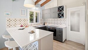 Una cocina moderna con una isla blanca, armarios grises y un salpicadero con diseño.