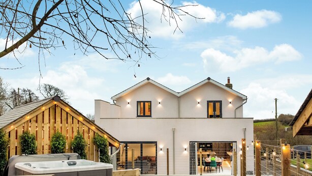 A modern two-story house with a hot tub, wooden deck, and outdoor seating area. - 5 bedroom accommodation in Atherington, near Umberleigh (Atherington, near Umberleigh)