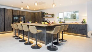 A modern kitchen with a central island, bar stools, pendant lighting, and built-in appliances. - 5 bedroom accommodation in Atherington, near Umberleigh (Atherington, near Umberleigh)