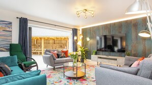 A modern living room with a sofa, armchairs, a coffee table, and a TV. - 5 bedroom accommodation in Atherington, near Umberleigh (Atherington, near Umberleigh)