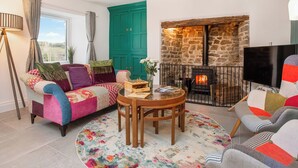 A cozy living room with a stone fireplace, a green door, and a colorful sofa. - 5 bedroom accommodation in Atherington, near Umberleigh (Atherington, near Umberleigh)