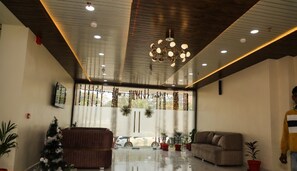 A spacious living area with a large window, a chandelier, and several pieces of furniture including a sofa and a chair.