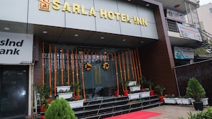 The exterior of Sarla Hotel Inn with a modern facade, a red carpet leading to the entrance, and potted plants around the entrance area. - Sarla Hotel Inn (Noida)
