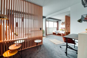 Una habitación de hotel moderna con un separador de madera, una cama, un escritorio y una silla.