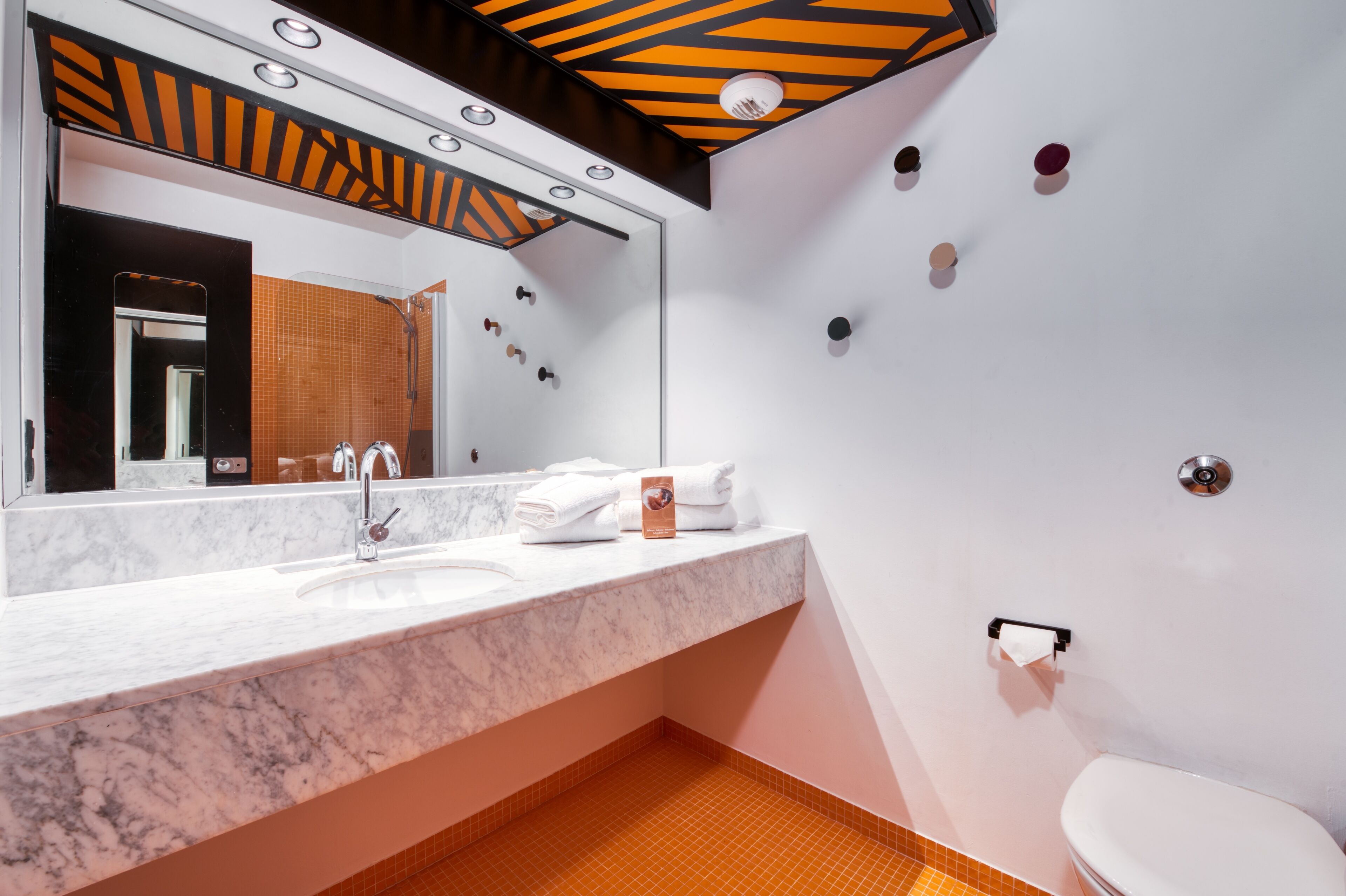 A modern bathroom with a marble sink, a large mirror, and a toilet.