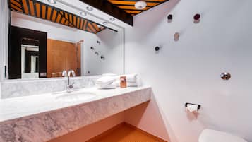 A modern bathroom with a marble sink, a large mirror, and a toilet.