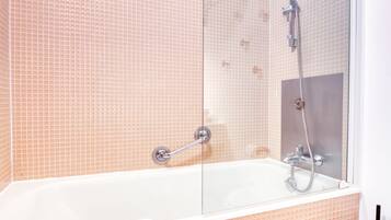 Un baño con ducha de vidrio, una bañera blanca y un lavamanos blanco.