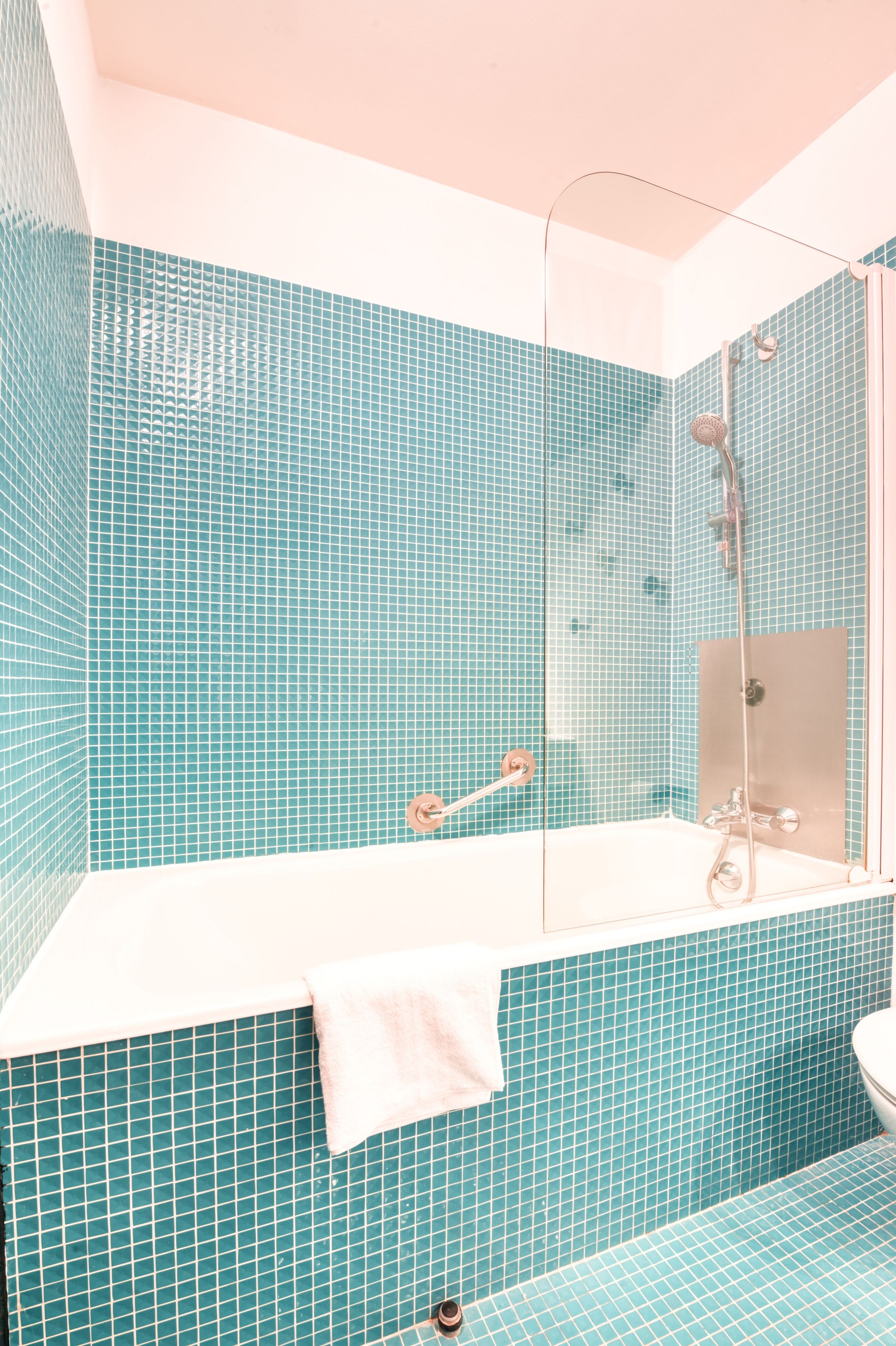 Une salle de bain avec une baignoire blanche, une douche à parois de verre et des murs recouverts de carreaux bleus.
