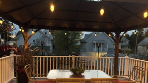 A covered outdoor seating area with a table and chairs, surrounded by a wooden deck and railing. - Romantic Villa (Troy)