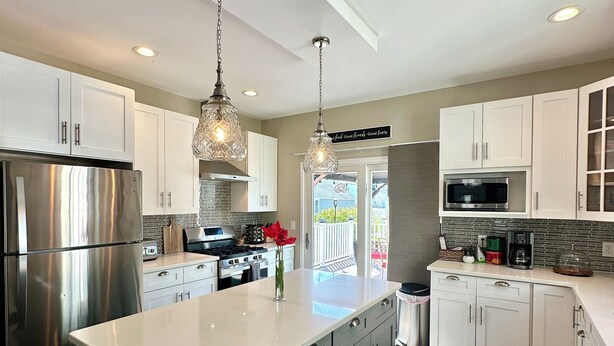 A modern kitchen with a large island, stainless steel appliances, and pendant lighting. - Romantic Villa (Troy)