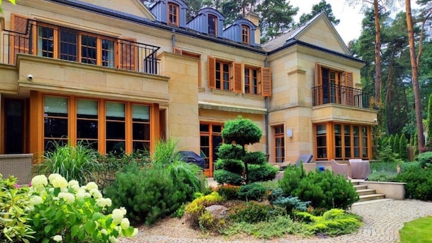 A two-story house with a well-maintained garden, a stone pathway, and a small staircase leading to a balcony. - Stately Home 25 mins to central Warsaw (Magdalenka)