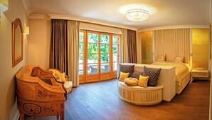 A spacious bedroom with a large bed, a curved seating area, and a view of the outdoors through a glass door. - Stately Home 25 mins to central Warsaw (Magdalenka)