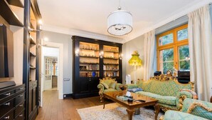 A spacious living room with a large bookshelf, a green sofa set, and a wooden coffee table. - Stately Home 25 mins to central Warsaw (Magdalenka)