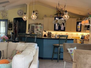 Enjoy a well-appointed kitchen with a central island, coffee machine, and dining area featuring a sofa and chair.