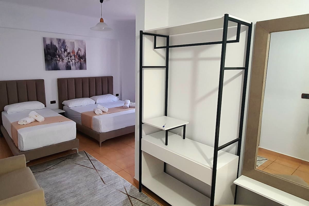 A hotel room with two beds, a large mirror, and a wall-mounted shelf unit.