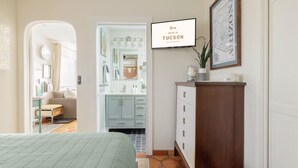 A bedroom with a bed, a dresser, and a TV displaying 'VACAT IN TUCSON'. - Oasis Casita by Vacay in Tucson - Guesthouse on 4 peaceful desert acres (Tucson)