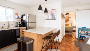 A compact kitchen with a central island, bar stools, a refrigerator, and a coffee maker. - Oasis Casita by Vacay in Tucson - Guesthouse on 4 peaceful desert acres (Tucson)