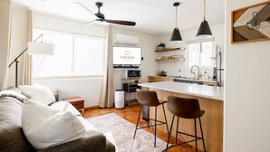 A modern kitchen with a bar area, a dining table, and a sofa with cushions. - Oasis Casita by Vacay in Tucson - Guesthouse on 4 peaceful desert acres (Tucson)