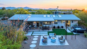 Ein modernes Haus mit Terrasse, Sitzgelegenheit im Freien und einem Whirlpool.