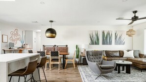 Een moderne woonkamer met een eethoek, een bank, een salontafel en een plafondventilator.