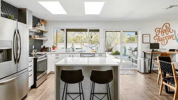 Een moderne keuken met een centraal eiland, barstoelen en uitzicht op de omgeving.