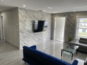 Relax in this stylish living room with a large flat-screen TV, glass coffee table, and comfortable sofa.