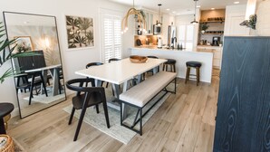 Une cuisine moderne dotée d’un îlot central, de meubles blancs et d’un luminaire suspendu.